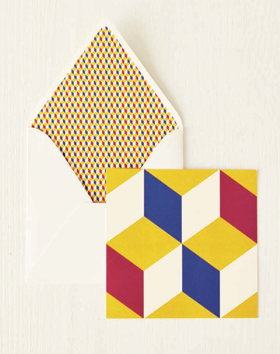 Yellow, blue, red, and cream cube-pattern note card beside an open envelope with a miniature matching geometric lining.